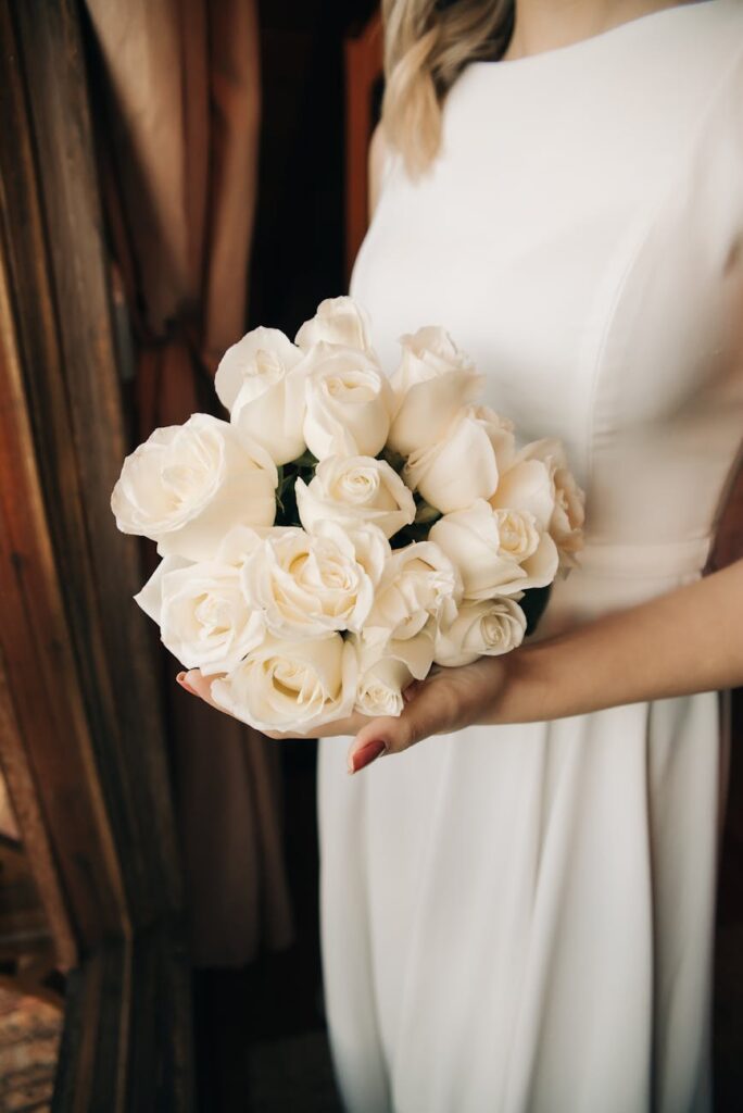 woman in white dress holding white bouquet