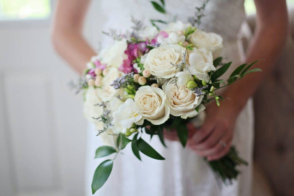 brides holding white bouquet of roses