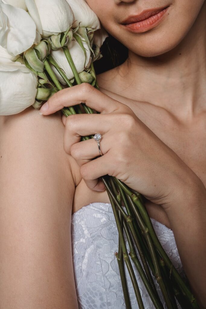 a woman in white lace wedding dress holding white roses