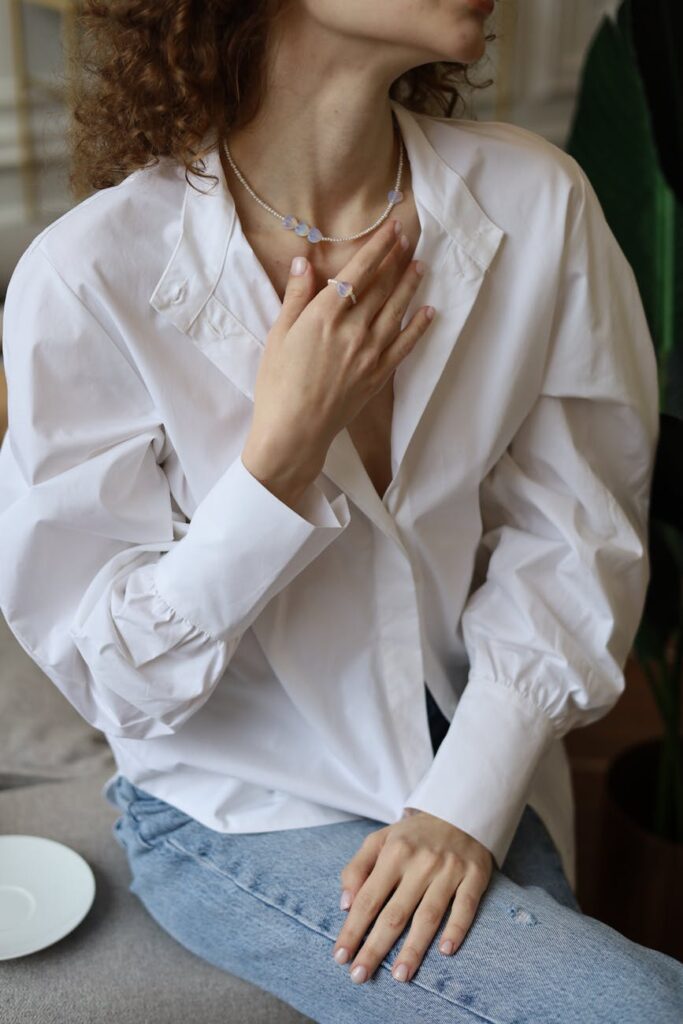 woman in oversized shirt touching her collarbone