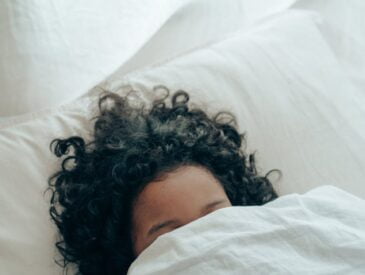 unrecognizable person sleeping under blanket