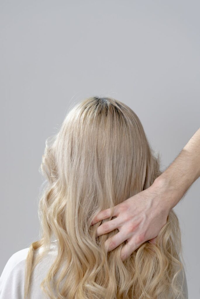 photo of a person s hand touching blond hair